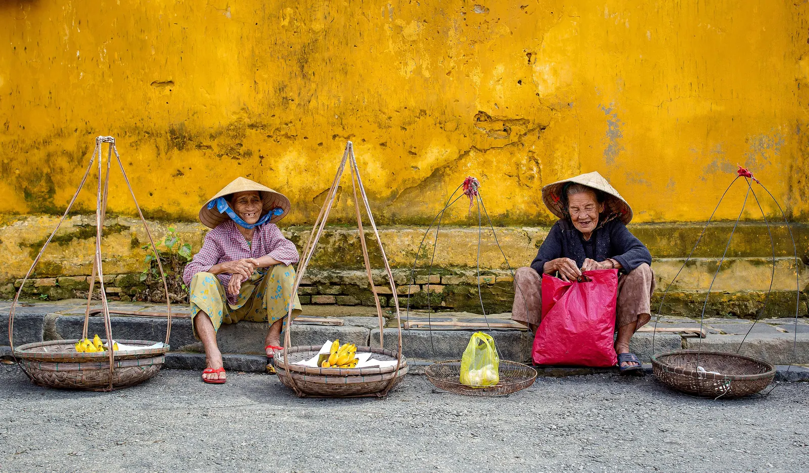 Street vendors beside a yellow wall in Vietnam